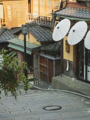 From above of unrecognizable female tourist standing on paved walkway near aged typical houses in Higashiyama district of Kyoto